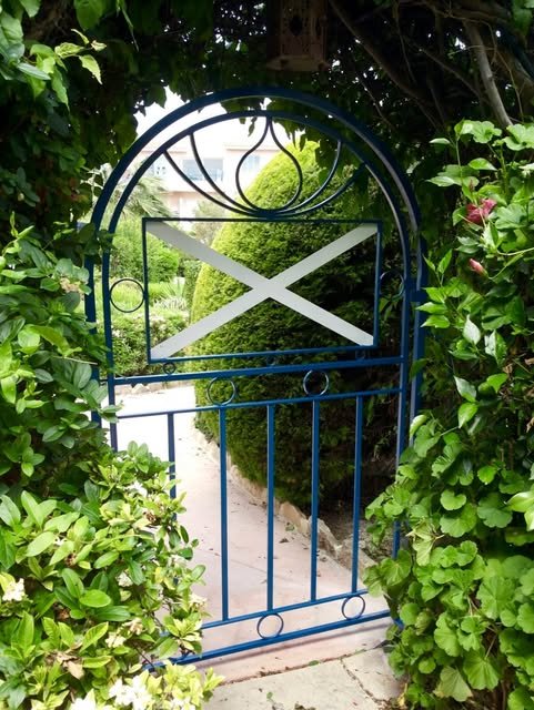 Decorative arched metal garden gate framed by climbing plants