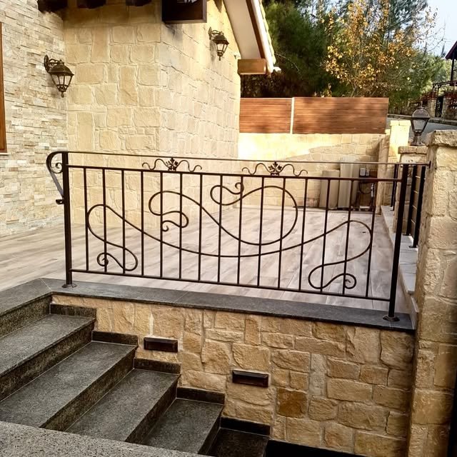 Decorative metal balcony railing beside a stone-clad exterior