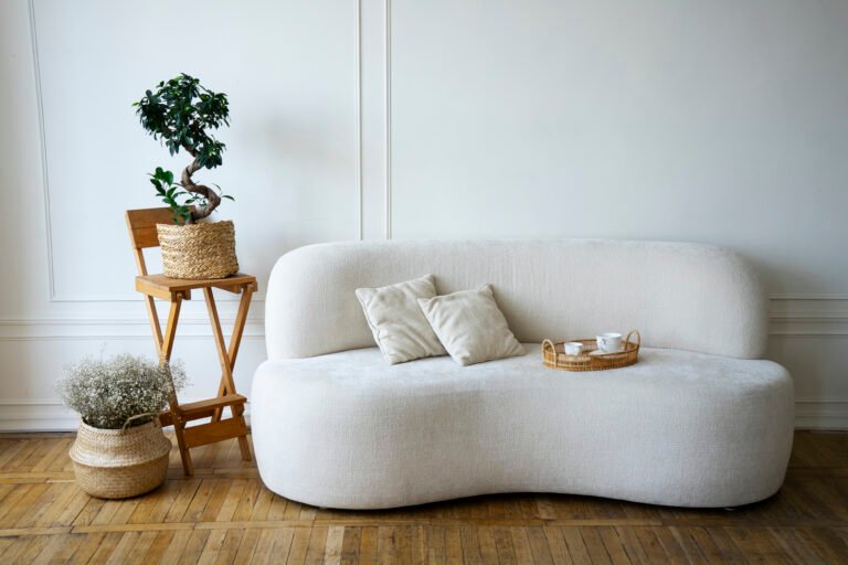 Living room with a sofa, potted plants and soft neutral furnishings