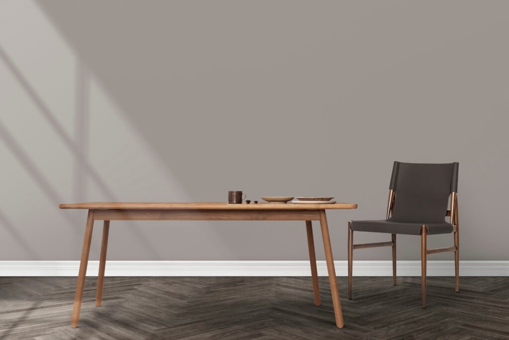 Slender wooden dining table and dark upholstered chair in a minimal interior