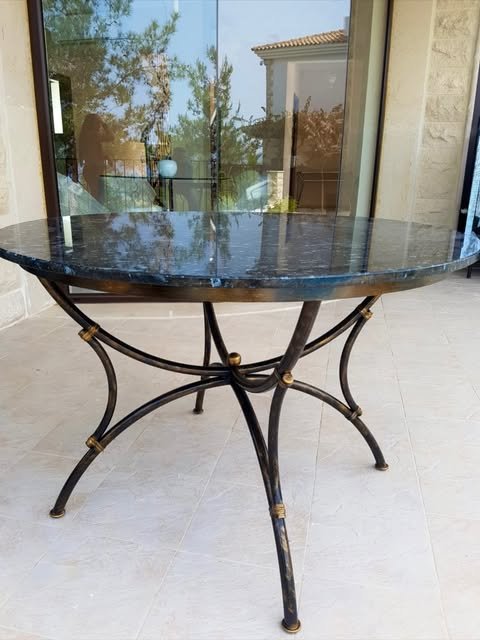 Round dark-topped table with a curved decorative metal base