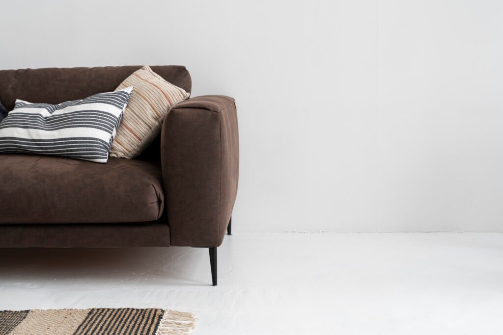 Brown upholstered sofa with textured cushions against a pale wall
