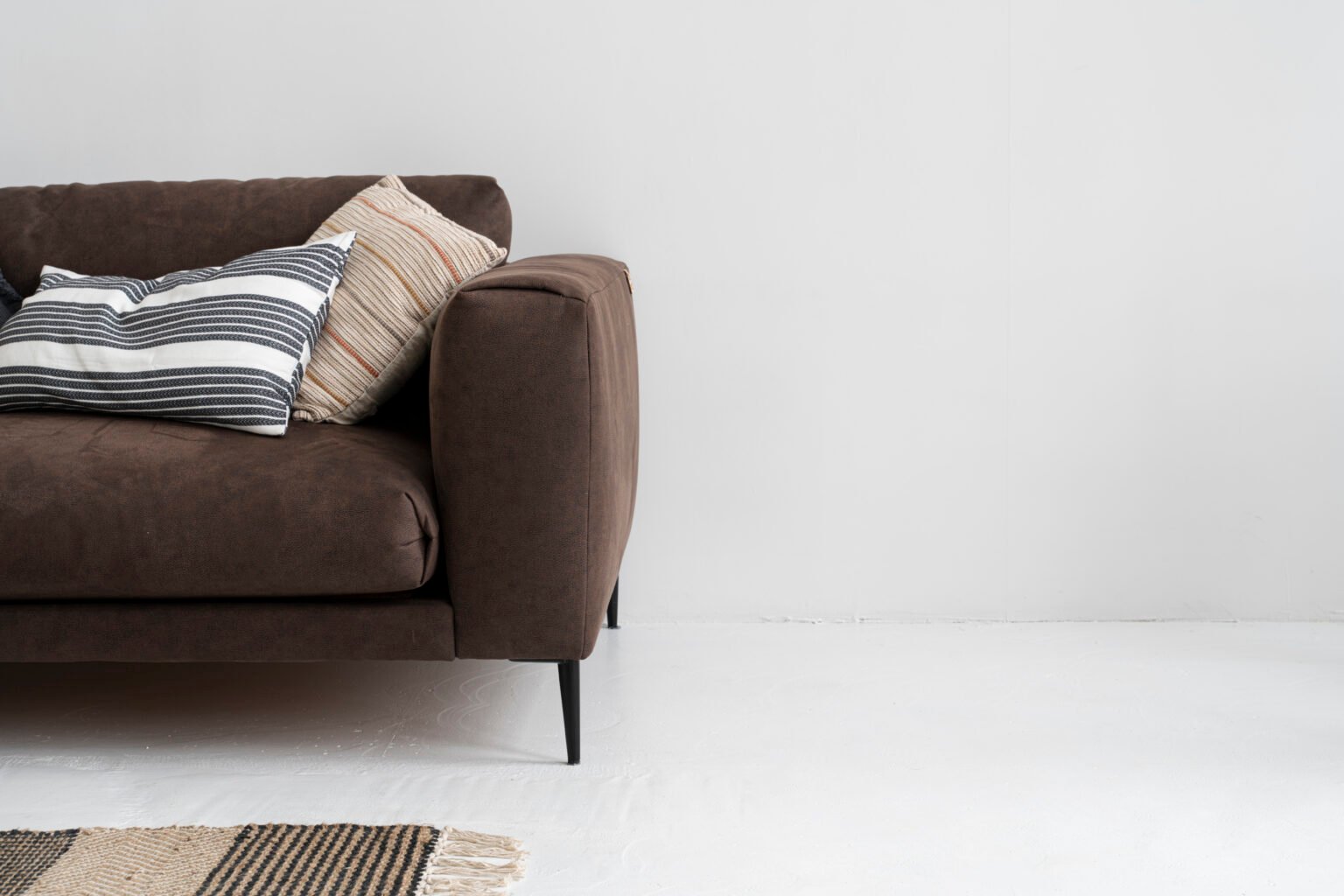 Brown upholstered sofa with textured cushions against a pale wall